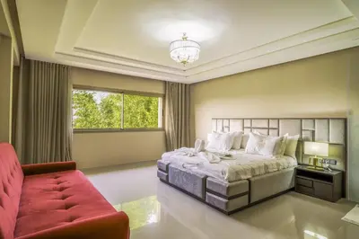 a bedroom with a large bed and a red couch at Villa Naciri en plein golf avec vue sur Atlas in Marrakech