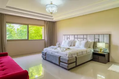 a bedroom with a large bed and a red couch at Villa Naciri en plein golf avec vue sur Atlas in Marrakech
