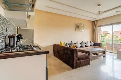 a kitchen and living room with a couch and a stove at Cozy Atlas Golf Studio Prestigia Marrakech in Marrakech