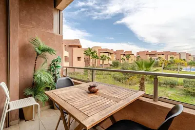 a balcony with a wooden table and a view of a city at Cozy Atlas Golf Studio Prestigia Marrakech in Marrakech