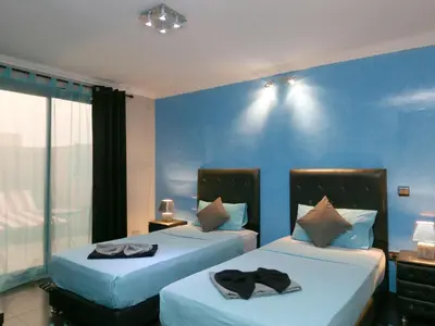 two beds in a room with blue walls at Ghita Appartement in Marrakech
