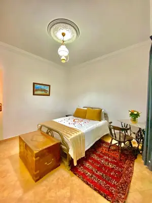 a bedroom with a bed and a table and a rug at Dar Baddi in Marrakech