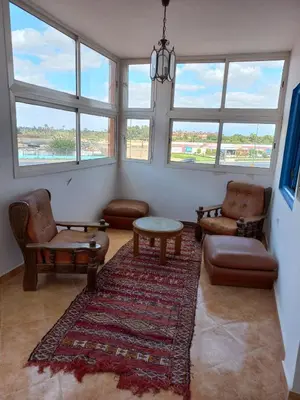 a living room with chairs and a table and windows at Dar Baddi in Marrakech
