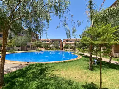 a swimming pool in a park with trees and buildings at Appartement marrakech de lux in Marrakech