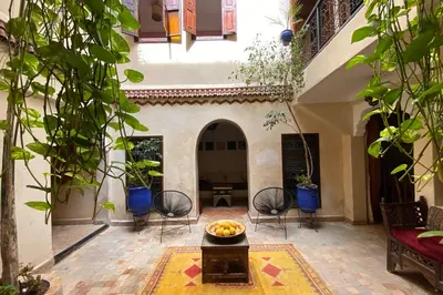a courtyard with chairs and a bowl of fruit on a table at Riad Of The Storks in Marrakech