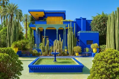 a fountain in front of a blue building with cactus at Appartement Nour 5 Marrakech Centre Gueliz avec piscine in Marrakech