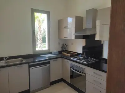 a kitchen with white cabinets and a black counter top at Villa isolée 4 façades avec piscine in Marrakech