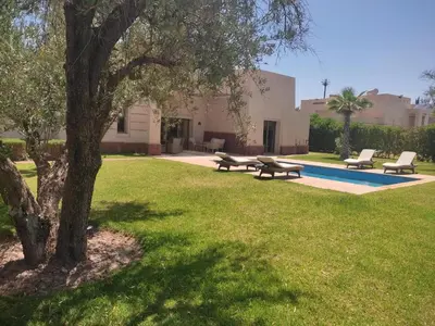 a park with two picnic tables and a tree at Villa isolée 4 façades avec piscine in Marrakech