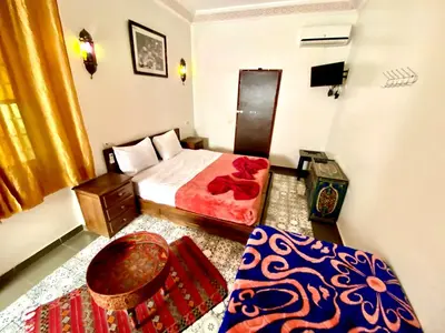a bedroom with a bed and a chair and a table at Riad Jibraile in Marrakech