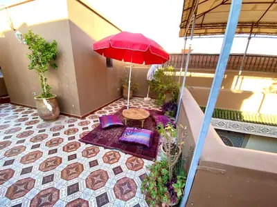 a balcony with a table and a red umbrella at Riad Jibraile in Marrakech