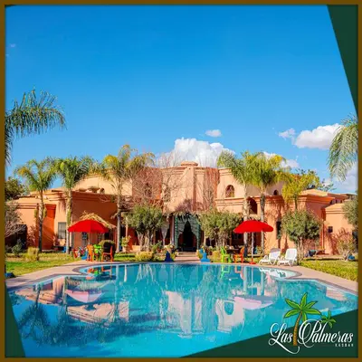 a resort with a swimming pool in front of a building at Las Palmeras Guest House in Marrakech