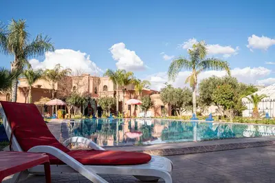 a chair next to a pool at a resort at Las Palmeras Guest House in Marrakech