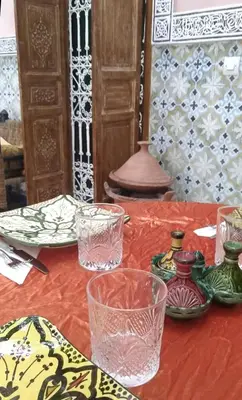 a table with glasses and plates on a red table cloth at Riad Bouchouari 33 in Marrakech