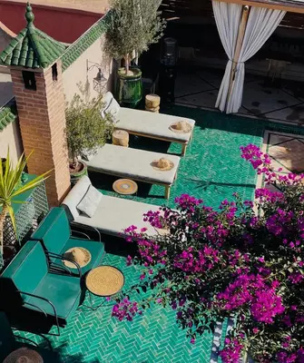 a patio with two chairs and purple flowers at Riad Ksar Al Amal & Spa in Marrakech