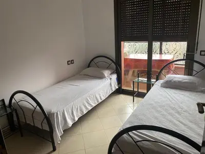 two beds are in a room with a window at Résidence Caprice Palace Hivernage in Marrakech