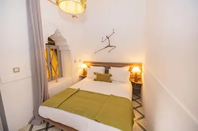 a bedroom with a bed with a green blanket on it at Riad Tizou in Marrakech