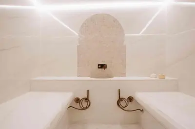 a white bathroom with two benches and an arch in the wall at Riad Nyla Wellness and Spa in Marrakech