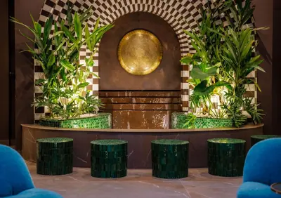 a lobby with green stools in front of a fountain at Riad Nyla Wellness and Spa in Marrakech