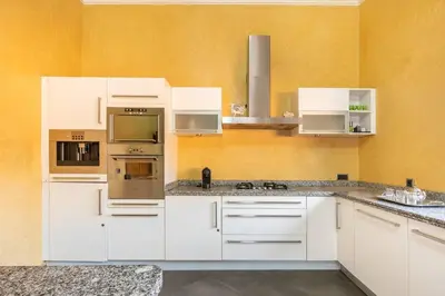 a kitchen with white cabinets and a yellow wall at Villa près de golfs in Marrakech