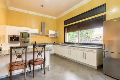 a kitchen with white cabinets and a large window at Villa près de golfs in Marrakech