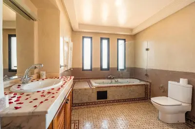 a bathroom with a tub and a toilet and a sink at Villa près de golfs in Marrakech