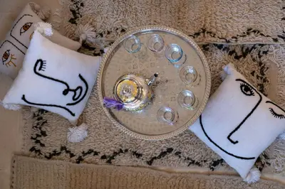 a clock sitting on a table with two pillows at Prestigia, superbe appartement, vue sur golf, piscine et Atlas in Marrakech