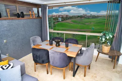a table and chairs with a view of a golf course at Prestigia, superbe appartement, vue sur golf, piscine et Atlas in Marrakech