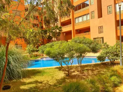a swimming pool in front of a building at Superbe appartement en résidence avec piscines in Marrakech