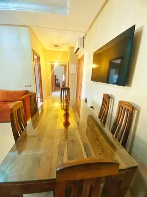 a dining room with a long table and chairs at Superbe appartement en résidence avec piscines in Marrakech