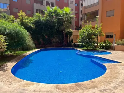 a blue swimming pool in the middle of a building at Superbe appartement en résidence avec piscines in Marrakech