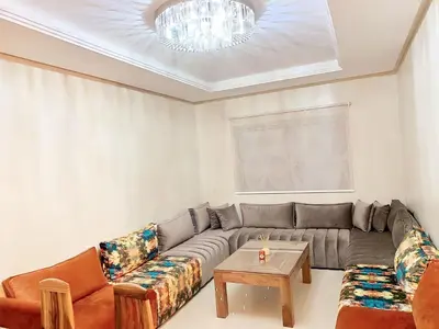 a living room with a couch and a table at Superbe appartement en résidence avec piscines in Marrakech
