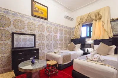 a hotel room with two beds and a table at Riad La Porte d'Or & SPA in Marrakech