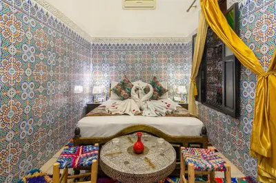 a bedroom with a bed and a table with chairs at Riad La Porte d'Or & SPA in Marrakech