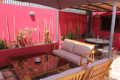 a patio with a couch and a table and a pink wall at Riad Hilmuna Hammam et Spa in Marrakech