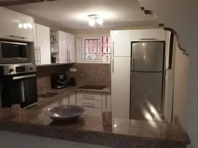 a kitchen with white cabinets and a refrigerator at Un Riad pour se divertir en famille & se détendre in Marrakech