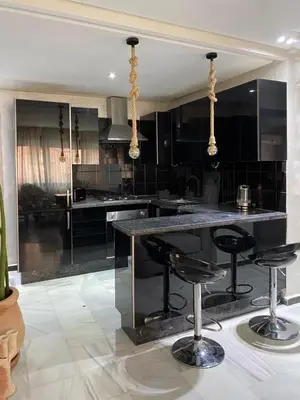 a large kitchen with black cabinets and bar stools at Vitality Home in Marrakech