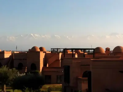 a group of buildings with snow covered mountains in the background at Atlas Views By Golf Resort in Marrakech