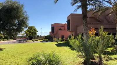 a building with a palm tree in a park at Atlas Views By Golf Resort in Marrakech