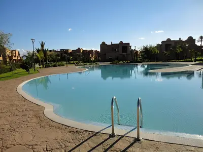 a large pool of blue water with buildings in the background at Atlas Views By Golf Resort in Marrakech