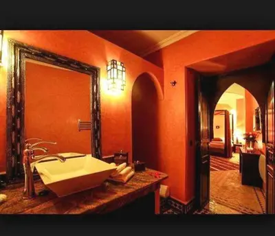 an orange bathroom with a sink and a mirror at Riad Mounlight in Marrakech