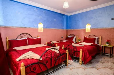 a bedroom with three beds with red sheets and blue walls at Hôtel Faouzi in Marrakech