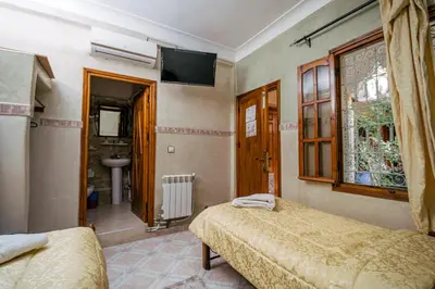 a bedroom with two beds and a bathroom with a sink at Hôtel Faouzi in Marrakech