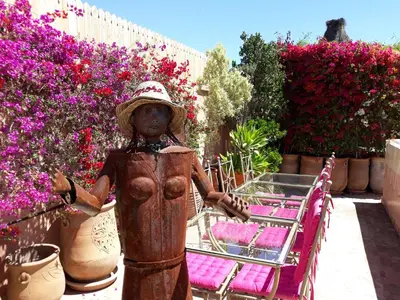 a statue of a woman standing next to chairs and flowers at Riad Jnane d'Ô in Marrakech