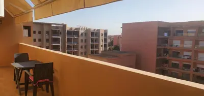 a balcony with two chairs and a table and some buildings at appart Marrakech in Marrakech