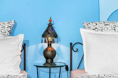 a lamp on a side table next to two beds at Riad La Famille in Marrakech