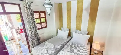 two twin beds in a room with a window at Riad La Famille in Marrakech