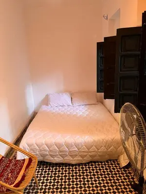 a small bedroom with a bed and a fan at Riad TaTam House in Marrakech