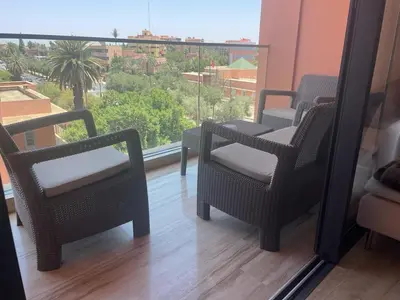 a balcony with wicker chairs and a large window at Superbe appartement à l Hivernage in Marrakech