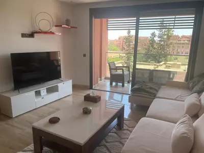 a living room with a couch and a tv at Superbe appartement à l Hivernage in Marrakech