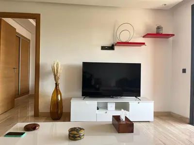 a living room with a tv and a white entertainment center at Superbe appartement à l Hivernage in Marrakech